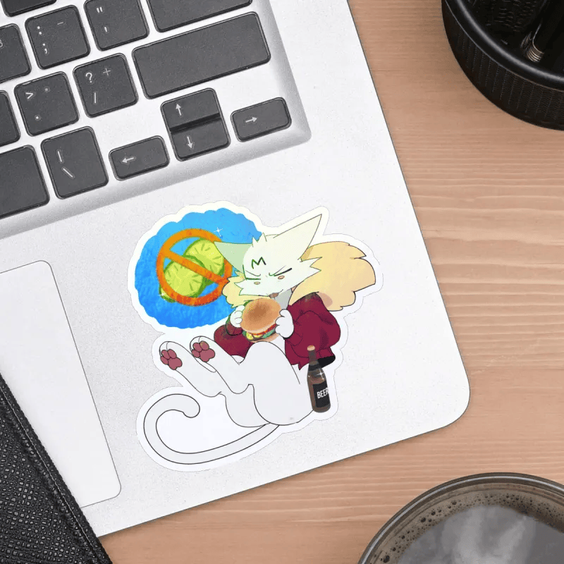 A die-cut vinyl sticker featuring an anime-style white cat character with yellow hair, wearing a red coat and holding a drink, placed on the corner of a silver laptop on a wooden desk.